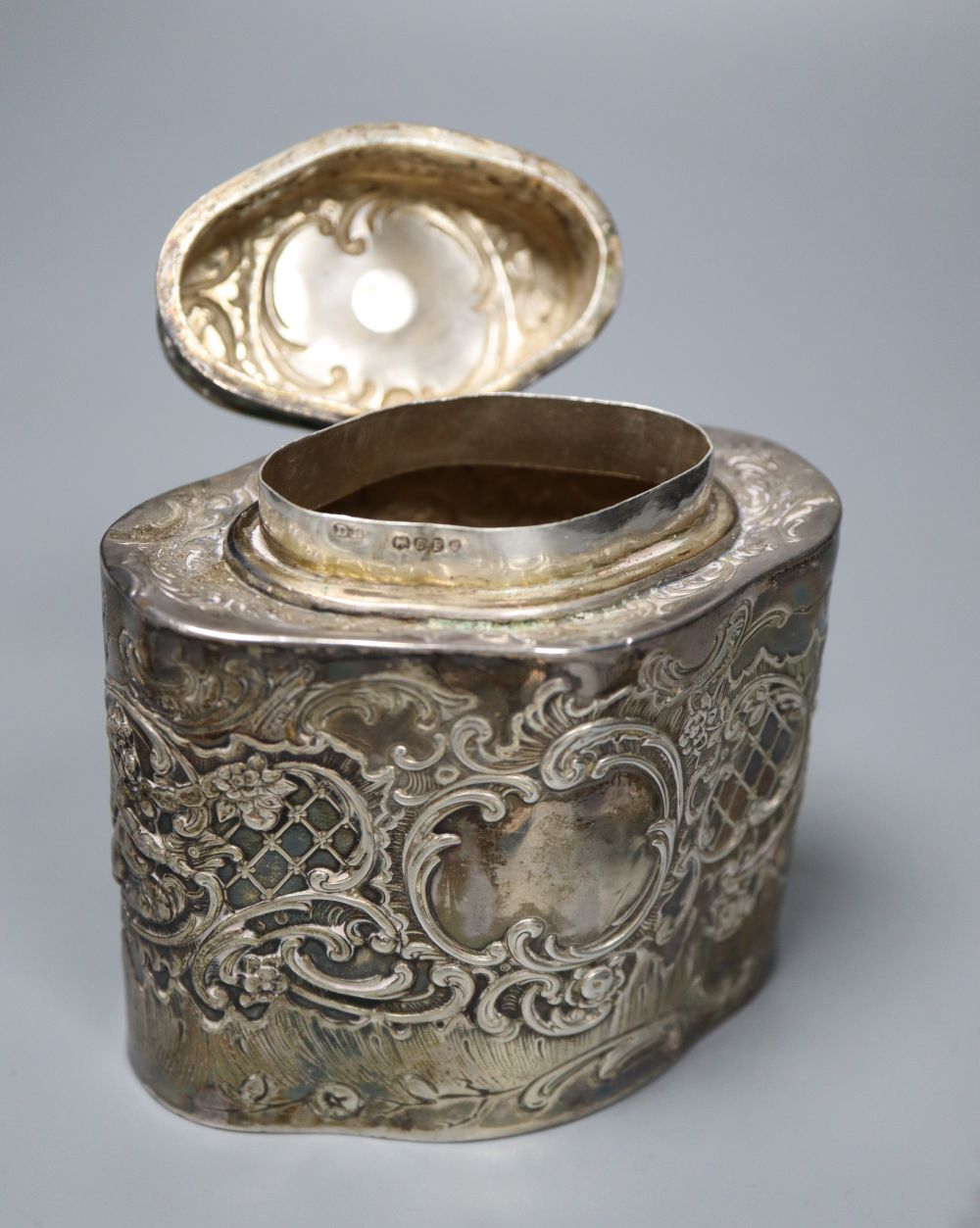 A Dutch oval silver tea caddy, embossed with cherubs and scrolls, 1893 import marks and four sifter spoons, various 5.5oz (caddy)